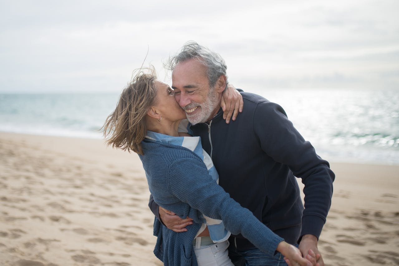 A mature couple enjoying a romantic moment on a Portuguese beach, symbolizing love and togetherness.